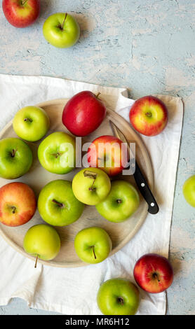 Des pommes rouges et vertes avec un couteau sur un sol en bois servant de sélection et une serviette blanche. Banque D'Images