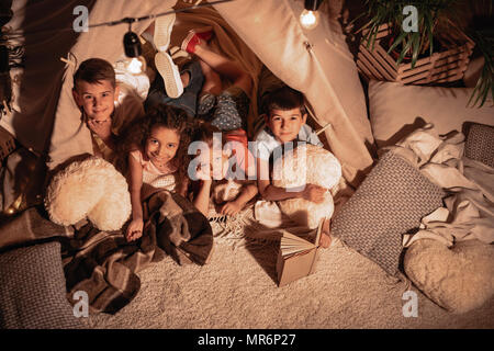 Groupe multi-ethnique des enfants reposant dans handmade tente à la maison Banque D'Images