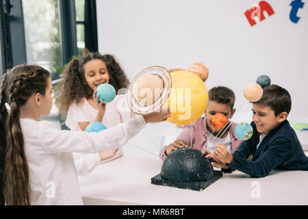 Groupe multiethnique d'élèves travaillant avec le modèle du système solaire dans la classe Banque D'Images