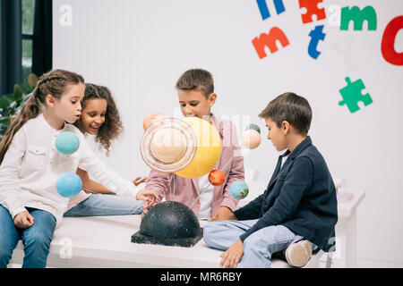 Groupe multiethnique d'élèves travaillant avec le modèle du système solaire dans la classe Banque D'Images