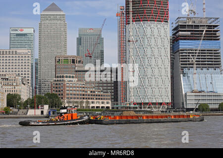 Un remorqueur barges contenant des conteneurs à déchets le long de la Tamise à Londres, au Royaume-Uni, en passant le Canary Wharf. Marée haute, journée ensoleillée. Banque D'Images