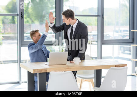 Des entrepreneurs ayant réussi, offrant un rapport cinq par ordinateur portable in modern office Banque D'Images