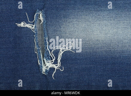 Coton Délavé Bleu indigo foncé denim jeans texture background avec le trou et les threads, Close up Banque D'Images