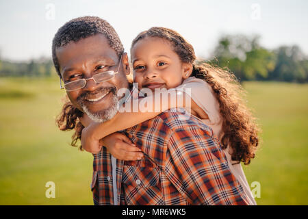 Happy african american granddaughter hugging her smiling grandfather sur pelouse verte Banque D'Images