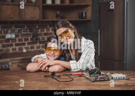 Petit-fils et sa belle mère serrant tout en étant assis à table avec carte mère sur elle Banque D'Images