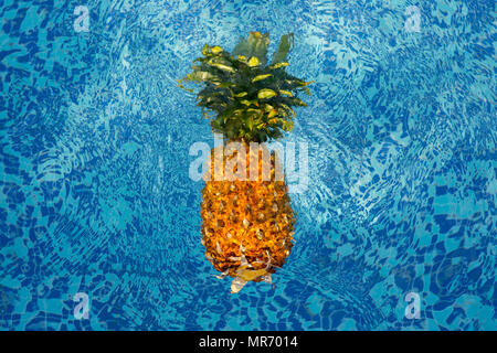 L'ananas flottant dans l'eau bleue de la piscine Banque D'Images