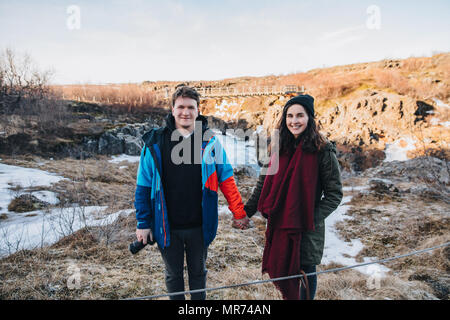 Happy young couple holding hands and smiling at camera while standing dans le magnifique paysage islandais Banque D'Images