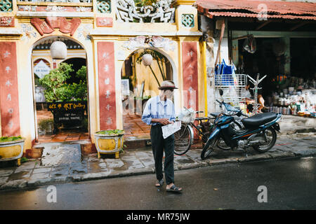 HOI AN, VIETNAM - 03 janvier, 2018 : senior homme vietnamien avec du papier journal marche sur rue dans Hoi An, Vietnam Banque D'Images