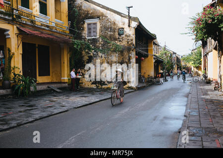 HOI AN, VIETNAM - 03 janvier, 2018 : les gens de chapeaux traditionnels la bicyclette sur rue dans Hoi An, Vietnam Banque D'Images