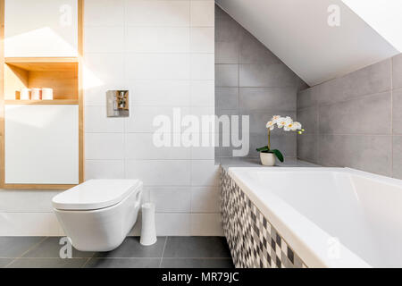 Salle de bains mansardée en gris et blanc avec baignoire et toilettes Banque D'Images