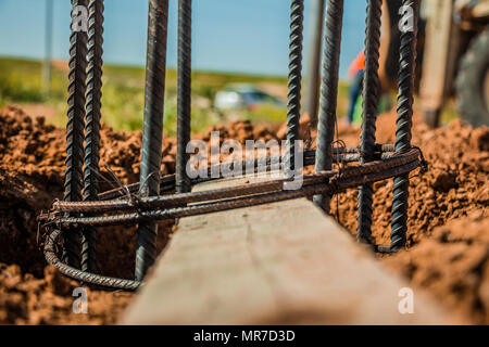 Barre d'acier utilisé pour la construction des poteaux avec renforcement du béton dans un trou dans le sol au chantier de construction. Banque D'Images