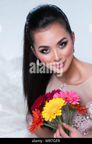 Young Asian woman with flowers portrait sur fond blanc Banque D'Images