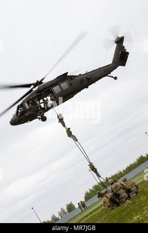 Les soldats de l'Opérations spéciales (FOS) Quitter un UH-60 Black Hawk de la compagnie C du bataillon d'hélicoptères d'assaut, 2-10, 10e Brigade d'aviation de combat, au cours d'une extraction et d'insertion de la corde rapide (frites) Formation à Lielvarde, la Lettonie, le 17 mai. La brigade et membres de la SOF lettons ont travaillé ensemble pendant une semaine entière à se qualifier pour les compétences à l'insertion de troupes d'élite des techniques telles que la ligne statique, parachutes, militaire en chute libre et des frites. (U.S. Photo de l'armée par la CPS. Thomas Scaggs) 170517-A-TZ475-166 Banque D'Images