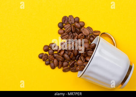 Les grains de café renversé sur une tasse sur le yellowbackground Banque D'Images