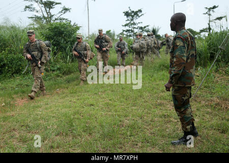 Les Forces armées du Ghana Le Sgt. Boakye-Danquah Joseph observe des soldats américains affectés au 1er Bataillon, 506e Régiment d'infanterie, 1e Brigade Combat Team, la 101e Division d'infanterie aéroportée, manoeuvre dans la jungle au cours de l'Accord de 2017 dans l'Akim Oda, Ghana, le 20 mai 2017. La Jungle Warfare School est une série d'exercices de formation de la situation visant à former les participants à la contre-insurrection et les opérations de sécurité interne. (U.S. Photo de l'armée par la FPC. Joseph Ami) Banque D'Images