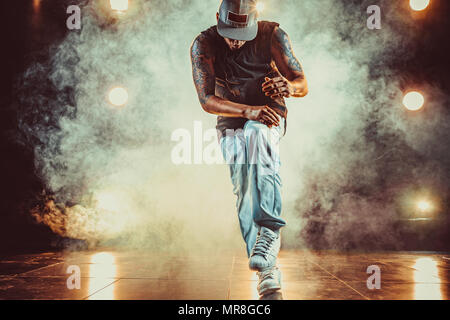 Jeune homme cool le break dance en club avec des lumières et de la fumée. Tatouage sur le corps. Banque D'Images