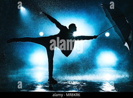 Jeune homme étrange danse avec parapluie sous la pluie. Bleu couleurs spectaculaires. Banque D'Images