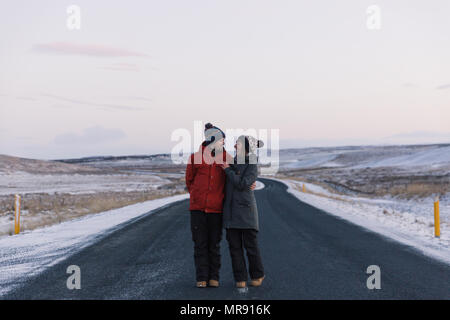 Happy young couple embracing, alors qu'il se trouvait sur la route d'asphalte en Islande Banque D'Images