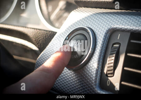 Girl appuyant sur le bouton d'arrêt du moteur sur le tableau de bord de voiture moderne Banque D'Images