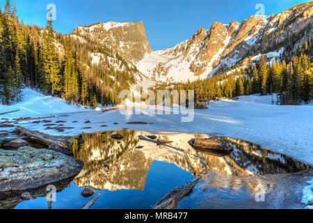 Soleil du matin sur pic Hallett est reflétée dans la moitié dans le lac gelé Dream Rocky Mountain National Park, Colorado Banque D'Images