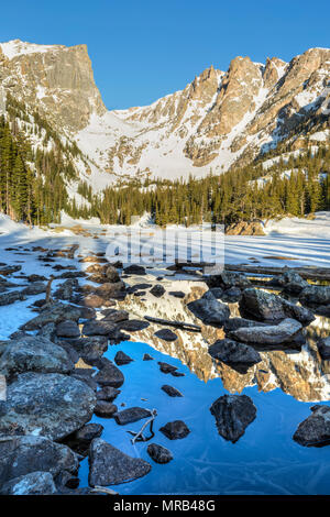Soleil du matin sur pic Hallett est reflétée dans la moitié dans le lac gelé Dream Rocky Mountain National Park, Colorado Banque D'Images
