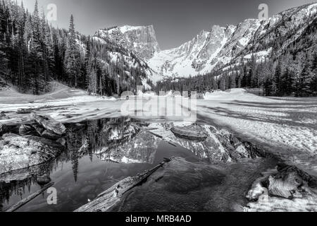 Soleil du matin sur pic Hallett est reflétée dans la moitié dans le lac gelé Dream Rocky Mountain National Park, Colorado Banque D'Images