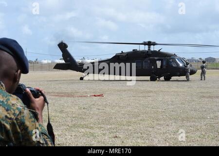 Un marin du Royal Bahamas Defence Force (RBDF) photographies de l'armée de soldats de la Garde nationale de Floride affecté à la Compagnie B, 1-185ème bataillon d'hélicoptères d'assaut, après qu'ils sortent leur UH-60L Black Hawk après leur atterrissage à base de Paragon. L'unité a visité la base de Paragon pour participer à un Tradewinds 2017 relations avec la communauté (COMREL) qui a accueilli des enfants des écoles locales pour rencontrer les membres des forces armées de plusieurs pays, poser des questions, et de vérifier leur équipement de près. Tradewinds est un joint, l'exercice combiné menée de concert avec les nations partenaires à fr Banque D'Images