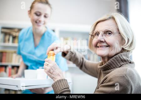 Ouverture Senior woman flacon de médicaments et de sourire. Banque D'Images