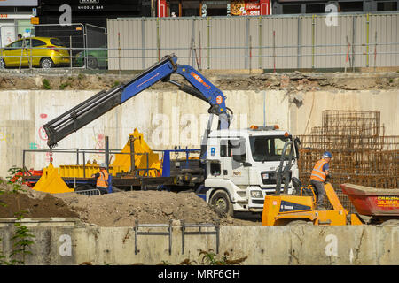 Un camion avec un bras hydraulique déchargement des matériaux de construction sur le site d'un nouveau bureau dans le centre-ville de Pontypridd Banque D'Images