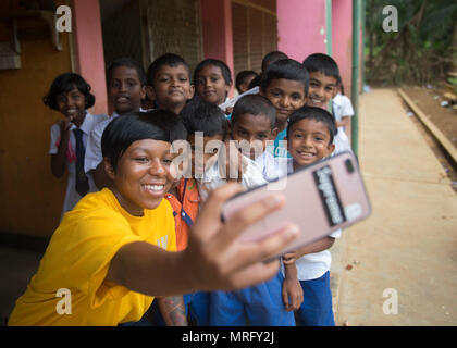 170614-N-MZ078-004 Galle, Sri Lanka (14 juin 2017) Spécialiste des opérations 3e classe Yvonne dent affectée à la classe Ticonderoga croiseur lance-missiles USS Lake Erie (CG 70) prend un '70623' avec les enfants de l'école. Nawodya Mallika Le lac Érié est au Sri Lanka pour soutenir les opérations d'aide humanitaire à la suite de graves inondations et glissements de terrain qui ont dévasté de nombreuses régions du pays. De fortes pluies récentes portées par une mousson de sud-ouest provoqué inondations et glissements de terrain dans tout le pays, le déplacement de milliers de personnes et causant des dommages importants aux habitations et bâtiments. Banque D'Images