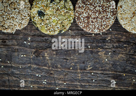 Dessert des collations aux céréales. Aliments diététiques de remise en forme. Kozinaki avec sésame, arachide, tournesol et graines de citrouille, les dates sur la vieille planche de bois rustique. Vegan healt Banque D'Images