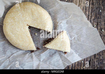 Des collations saines desserts sucrés. Aliments diététiques de remise en forme. Forme ronde halva sésame chocolat et coco combiné avec bouchon de remplissage sur la vieille planche de bois rustique. Veg Banque D'Images