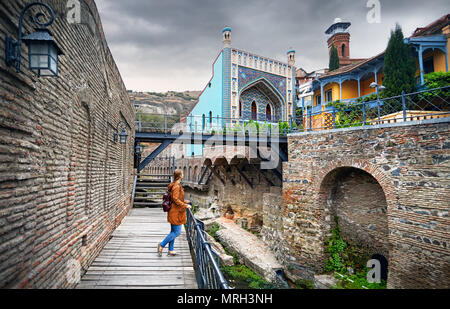 Femme veste marron en tourisme marche dans les vieilles rues de la baignoire sulfurique, dans le centre de Tbilissi, Géorgie Banque D'Images