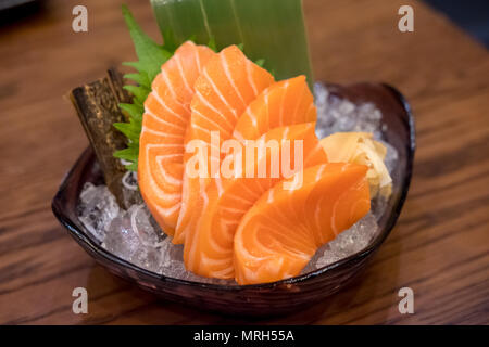 Sashimi de saumon avec les légumes et la glace dans un bol, servi dans un restaurant. Banque D'Images