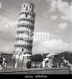 Années 1950, vue historique, les vendeurs de rue à l'extérieur de la Tour de Pise, Italie. Le campanile ou pose libre clocher est célèbre dans le monde entier pour son inclinaison imprévue, due à l'insuffisance de fondation sur sol mou lorsque sa a été construit. Sauvée d'un coup d'artillerie pendant la seconde guerre mondiale, de sorte que l'histoire continue, parce qu'il était considéré comme trop belle pour détruire, l'industrie touristique de Pise est à jamais reconnaissants. Banque D'Images