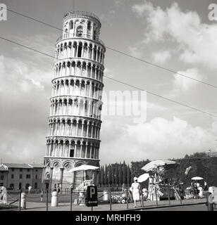 Années 1950, vue historique, les vendeurs de rue à l'extérieur de la Tour de Pise, Italie. Le campanile ou pose libre clocher est célèbre dans le monde entier pour son inclinaison imprévue, due à l'insuffisance de fondation sur sol mou lorsque sa a été construit. Sauvée d'un coup d'artillerie pendant la seconde guerre mondiale, de sorte que l'histoire continue, parce qu'il était considéré comme trop belle pour détruire, l'industrie touristique de Pise est à jamais reconnaissants. Banque D'Images