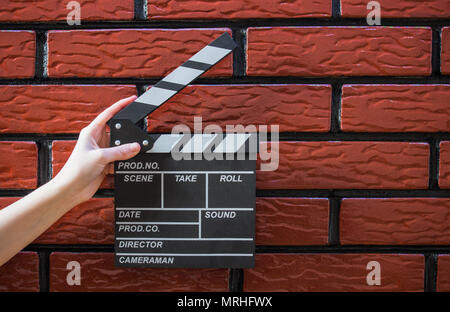 Les plaques à clapet, women's hands et un film avec un clapet de fond brique Banque D'Images