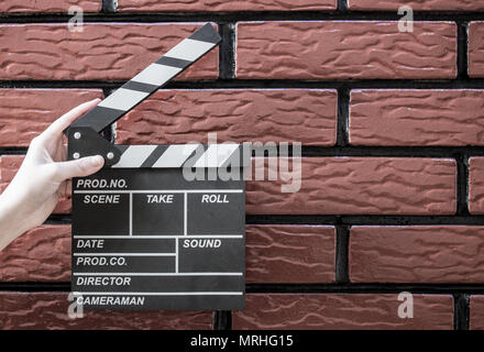 Les plaques à clapet, women's hands et un film avec un clapet de fond brique Banque D'Images