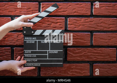 Les plaques à clapet, women's hands et un film avec un clapet de fond brique Banque D'Images