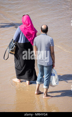 Femme portant un foulard hijab pagayant sur la plage. Angleterre, Royaume-Uni Banque D'Images