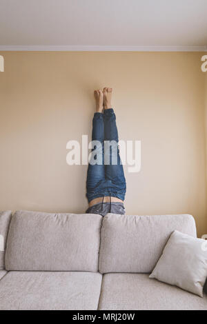 Homme handstanding derrière la table, le yoga et le nettoyage de printemps, concept de soins mobilier Banque D'Images