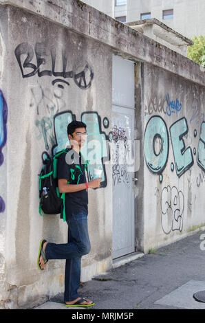 Portrait de jeune adulte jeune Indien posant contre un mur de graffiti avec sac à dos, à la recherche vers la caméra. Banque D'Images