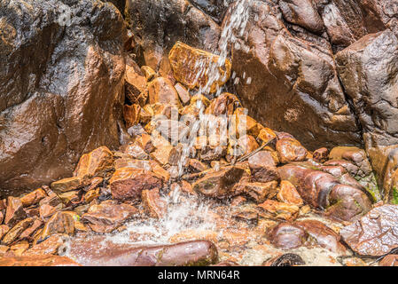 Petite cascade dans les rochers et les pierres en mousse par la plage Banque D'Images