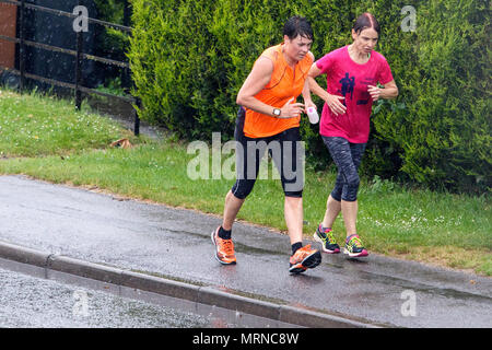Chippenham, UK, 27 mai 2018. Deux femmes sur la course sont illustrés bravant la forte pluie à Chippenham aussi lourds orages font leur chemin à travers le sud de l'Angleterre. Credit : lynchpics/Alamy Live News Banque D'Images