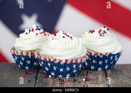 4 juillet patriotique ou Memorial Day celebration cupcakes. Le drapeau américain en arrière-plan. Banque D'Images