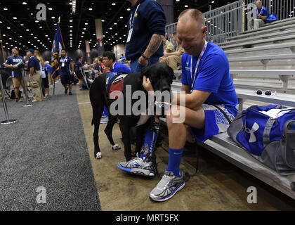 CHICAGO (juin 30,2017) a pris sa retraite de la Force aérienne Le Capitaine Chris Cochrane, montres Hans, un chien, pour le DoD Warrior participant Jeu Air Force Staff Sgt. Justin R. Fuchs. La DoD Warrior Jeux sont un événement annuel permettant aux blessés, malades et blessés militaires et anciens combattants à la concurrence dans les sports paralympiques-style dont le tir à l'arc, randonnée à vélo, terrain, tir, le volleyball assis, natation, athlétisme et de basket-ball en fauteuil roulant. (Photo du département de la communication de masse par marin spécialiste 675Landa) Banque D'Images