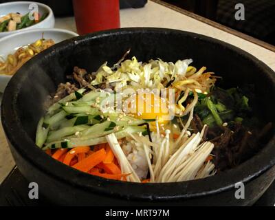 Bibimbap est un favori traditionnel coréen composé de riz vapeur, garni de viande, d'oeufs crus, champignons, et les légumes et habituellement servi dans un bain st Banque D'Images