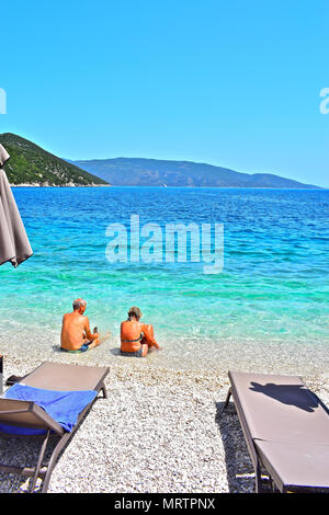 Un vieux couple s'amusant et profiter assis dans les eaux cristallines de la mer Ionienne, à proximité de Plage d'Antisamos Sami, Kefalonia, Grèce. Banque D'Images