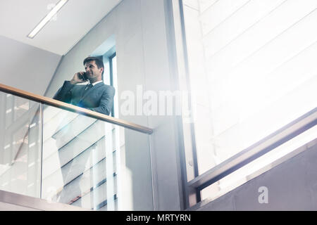 Low angle view businessman standing by railing et talking on mobile phone. Gestionnaire de bureau un appel téléphonique dans le bureau. Banque D'Images