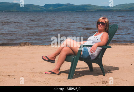 Femme à la retraite en vacances assis à la plage Lac Maskinonge St-Gabriel-de-Brandon Québec Canada Banque D'Images